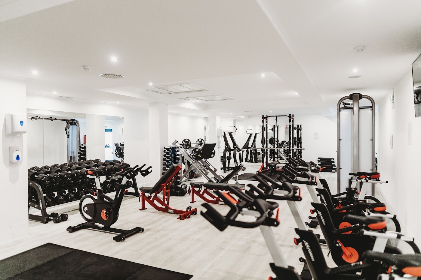Full gym floor showing dumbbell rack, benches, bikes and multi-station equipment